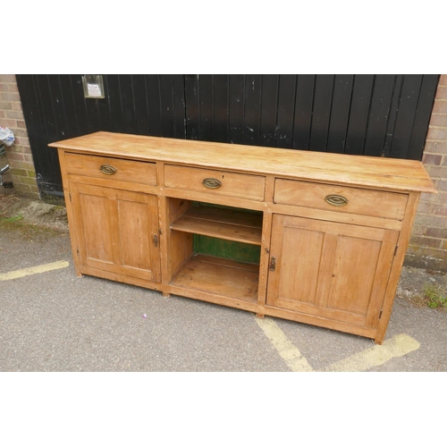 1121 - An early C19th stripped pine dresser base, three drawers over two cupboards flanking a dog kennel, r... 