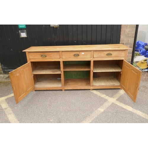 1121 - An early C19th stripped pine dresser base, three drawers over two cupboards flanking a dog kennel, r... 