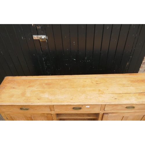 1121 - An early C19th stripped pine dresser base, three drawers over two cupboards flanking a dog kennel, r... 