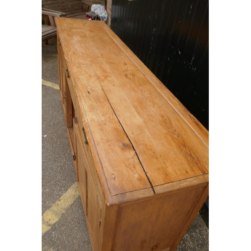 1121 - An early C19th stripped pine dresser base, three drawers over two cupboards flanking a dog kennel, r... 