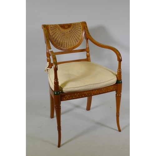 1128 - A Regency style open arm chair with caned back and seat and hand painted decoration, raised on sabre... 