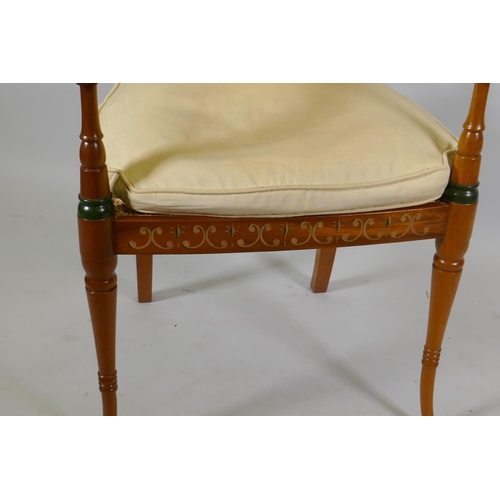 1128 - A Regency style open arm chair with caned back and seat and hand painted decoration, raised on sabre... 