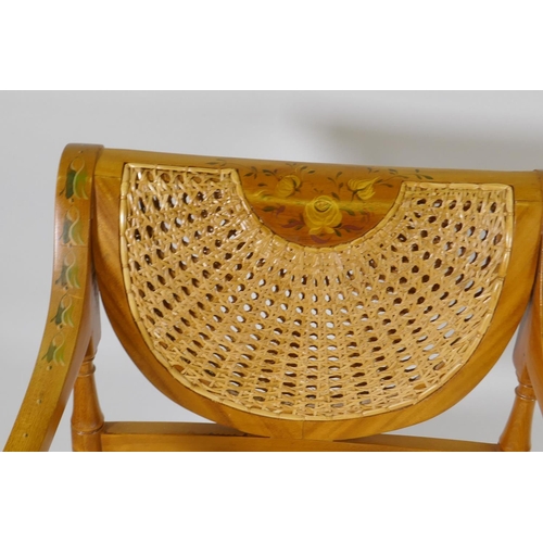 1128 - A Regency style open arm chair with caned back and seat and hand painted decoration, raised on sabre... 