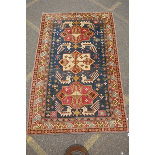 1150 - A blue ground wool Kazak carpet decorated with three medallions, with pink and cream borders, 172 x ... 