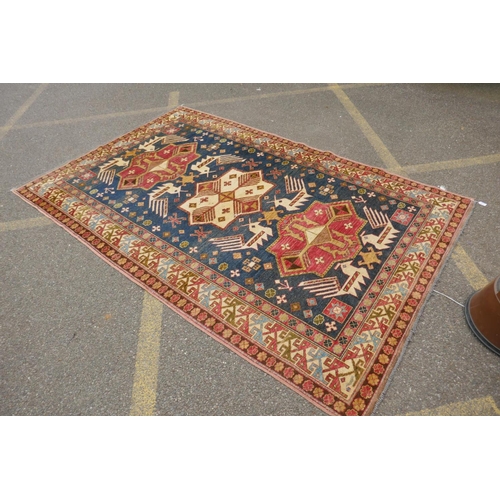 1150 - A blue ground wool Kazak carpet decorated with three medallions, with pink and cream borders, 172 x ... 