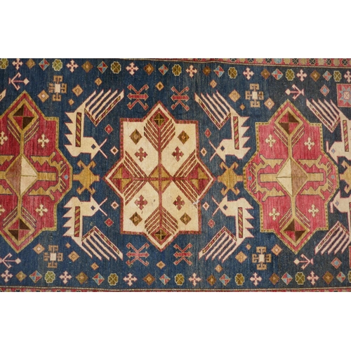 1150 - A blue ground wool Kazak carpet decorated with three medallions, with pink and cream borders, 172 x ... 