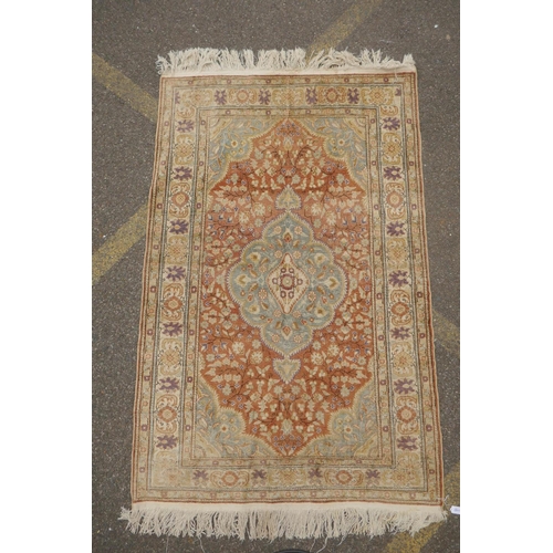 1157 - A Turkish faded silk rug with blue central medallion on a coral field, 120 x 184cm