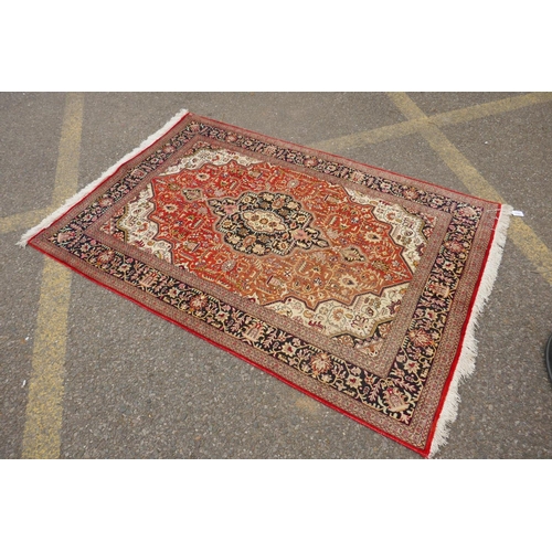 1161 - A Persian terracotta ground silk Heriz rug with black borders, 102 x 148cm