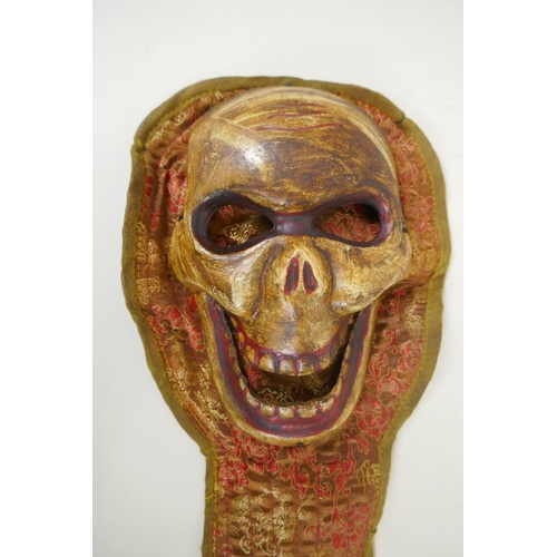 119 - A Tibetan ceramic Citipati death mask on a silk mount, 45cm long