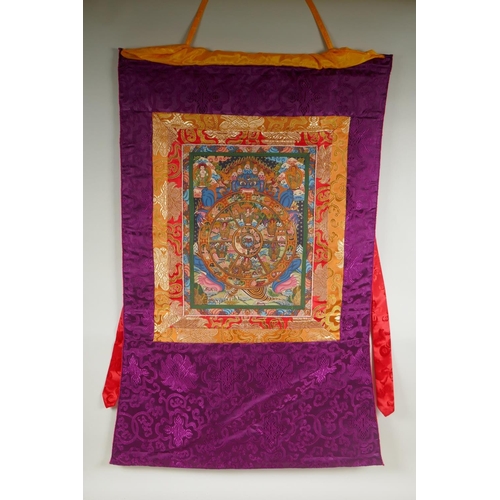 138 - A Tibetan painted thangka depicting the Buddhist wheel of life, in a silk mount, 56 x 81cm