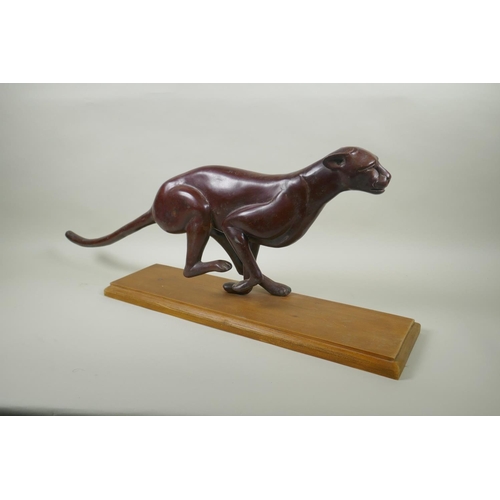 16 - A bronzed white metal figure of a running jaguar, mounted on a wood base, 68cm long