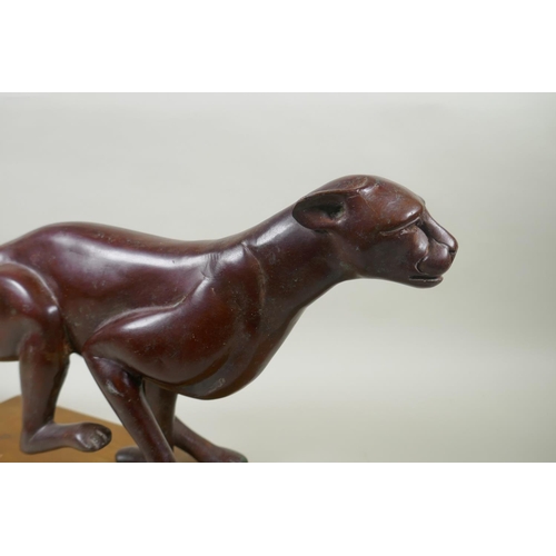 16 - A bronzed white metal figure of a running jaguar, mounted on a wood base, 68cm long