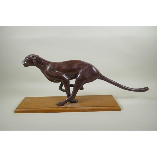 16 - A bronzed white metal figure of a running jaguar, mounted on a wood base, 68cm long