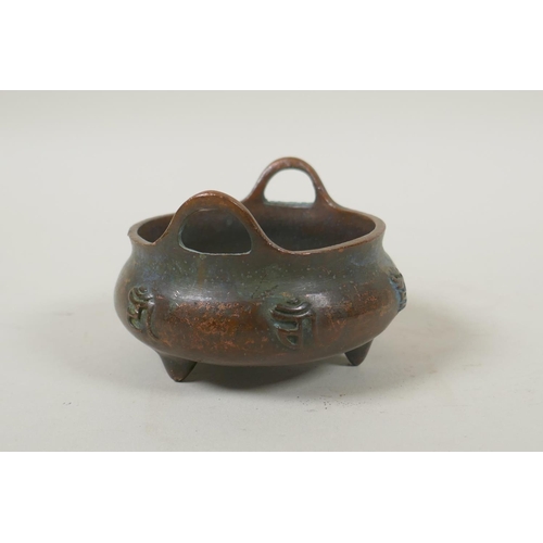 181 - A Chinese bronze two handled censer on tripod supports, with raised character decoration, impressed ... 