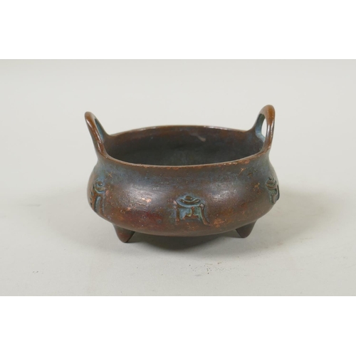 181 - A Chinese bronze two handled censer on tripod supports, with raised character decoration, impressed ... 