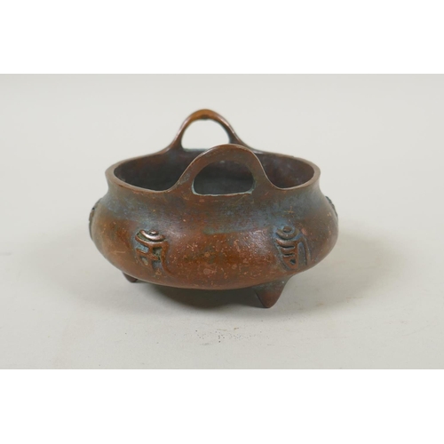 181 - A Chinese bronze two handled censer on tripod supports, with raised character decoration, impressed ... 