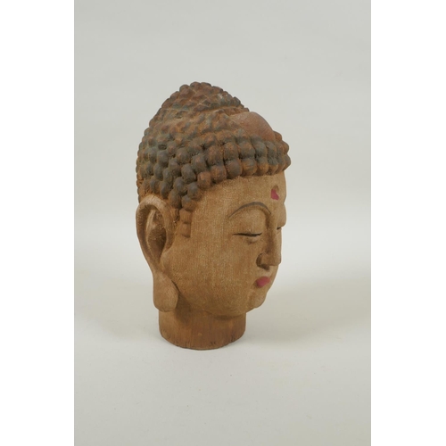 213 - A Chinese carved, painted and distressed wood Buddha head, 21cm high