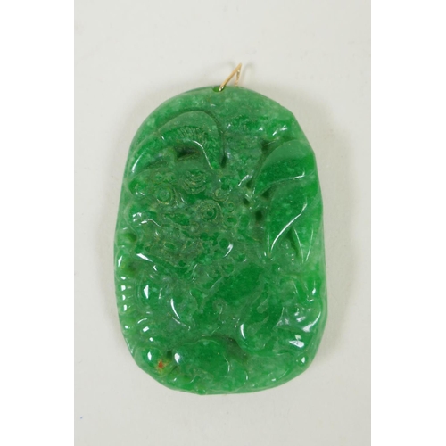 218 - A Chinese apple green jade pendant with carved temple lion decoration, 4 x 6cm