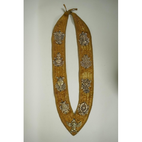 270 - A Tibetan silk sash affixed with metal mounts depicting the eight Buddhist treasures, 74cm long