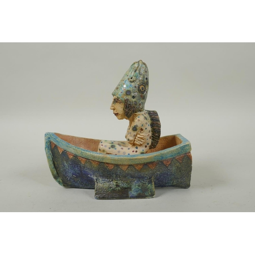 39 - An Amanda Popham (b.1954) studio pottery figure wearing a fish head riding in a boat, signed and dat... 