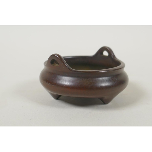 99 - A Chinese miniature bronze censer with phoenix eye handles and tripod supports, impressed seal mark ... 