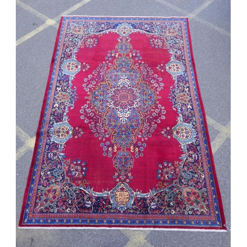 1010 - A rich red ground vintage Persian Mashad carpet with traditional floral medallion with signature of ... 