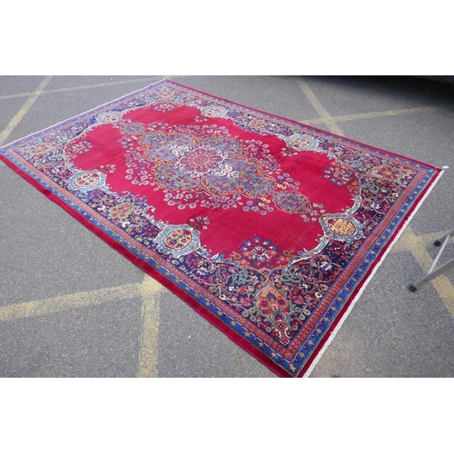 1010 - A rich red ground vintage Persian Mashad carpet with traditional floral medallion with signature of ... 