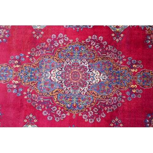 1010 - A rich red ground vintage Persian Mashad carpet with traditional floral medallion with signature of ... 