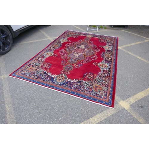 1010 - A rich red ground vintage Persian Mashad carpet with traditional floral medallion with signature of ... 