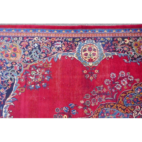 1010 - A rich red ground vintage Persian Mashad carpet with traditional floral medallion with signature of ... 