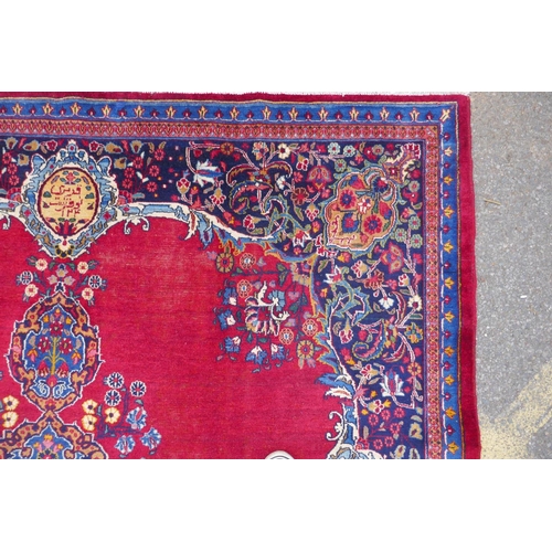 1010 - A rich red ground vintage Persian Mashad carpet with traditional floral medallion with signature of ... 