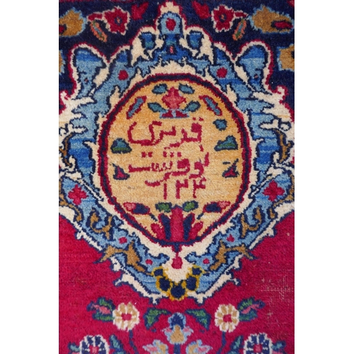 1010 - A rich red ground vintage Persian Mashad carpet with traditional floral medallion with signature of ... 