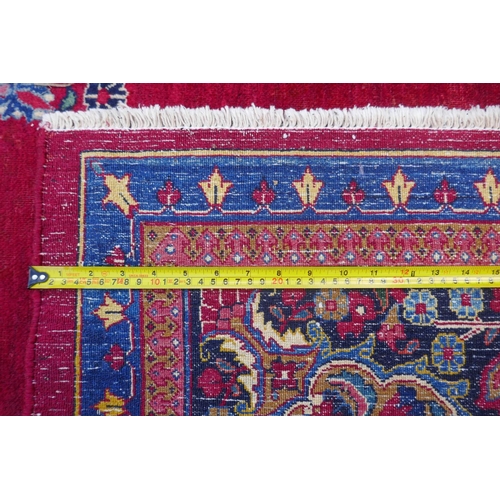 1010 - A rich red ground vintage Persian Mashad carpet with traditional floral medallion with signature of ... 