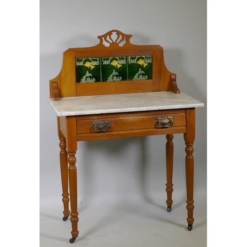 1011 - An Edwardian satin walnut single drawer wash stand with inset tiled back and marble top, raised on t... 