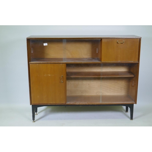 1054 - A mid century Nathan sapele side cabinet with sliding glass doors and two cupboards raised on ebonis... 