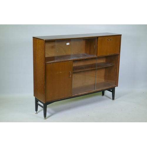 1054 - A mid century Nathan sapele side cabinet with sliding glass doors and two cupboards raised on ebonis... 