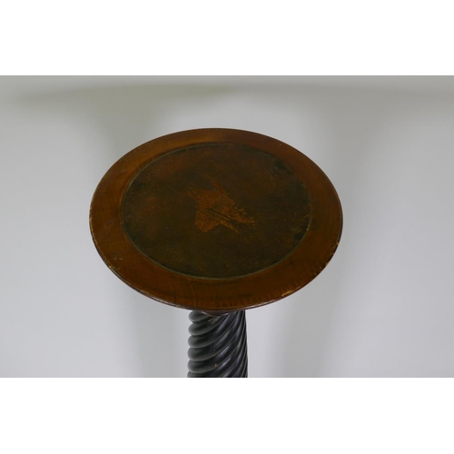 1061 - A mahogany torchere with leather inset top, raised on twisted column with carved base, 28cm diameter... 