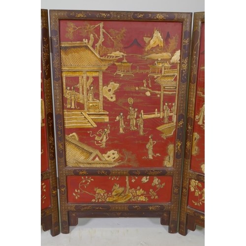 1083 - A C19th Chinese export three fold red lacquered fire screen with raised gilt chinoiserie decoration,... 