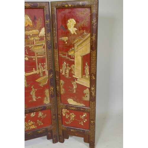 1083 - A C19th Chinese export three fold red lacquered fire screen with raised gilt chinoiserie decoration,... 