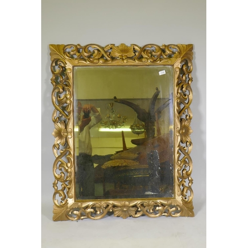 1125 - A carved and pierced giltwood Florentine style wall mirror with bevelled glass, late C19th/early C20... 