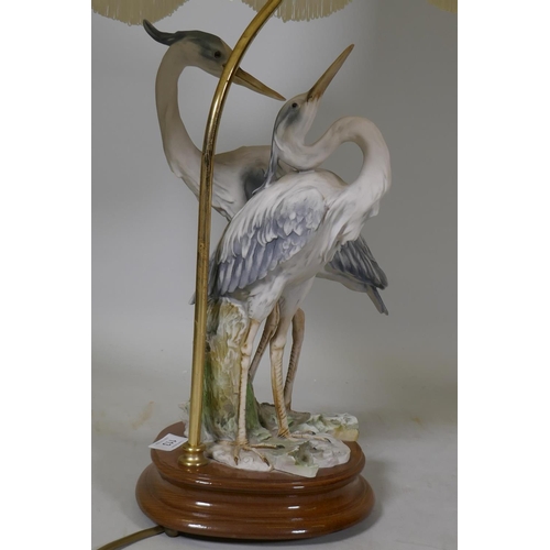 113 - A composition table lamp in the form of a pair of herons, with shade, 80cm high