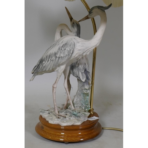 113 - A composition table lamp in the form of a pair of herons, with shade, 80cm high