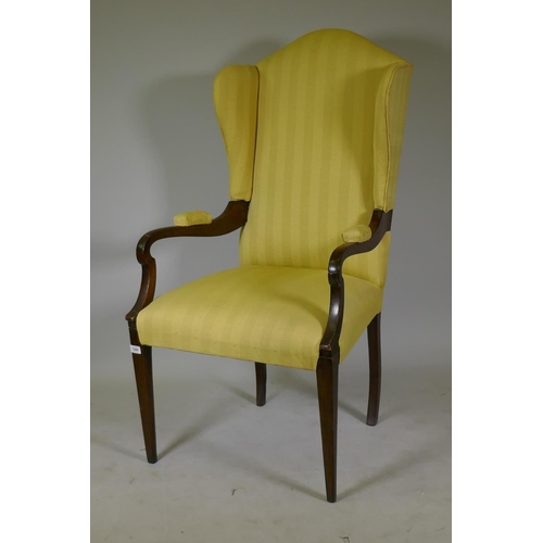 1164 - An Arts & Crafts mahogany wing back armchair with open arms, raised on square tapering supports ... 