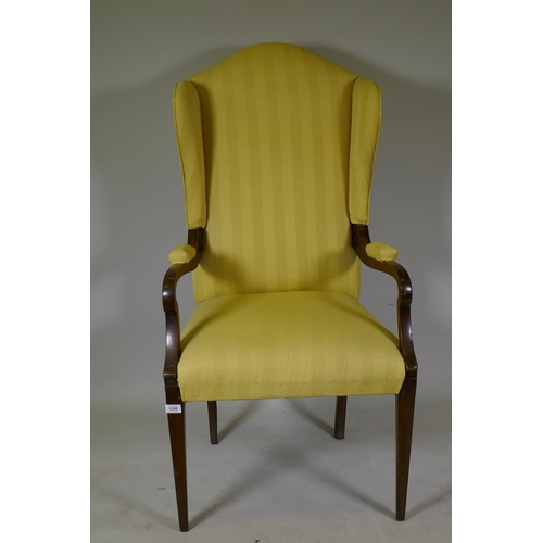 1164 - An Arts & Crafts mahogany wing back armchair with open arms, raised on square tapering supports ... 