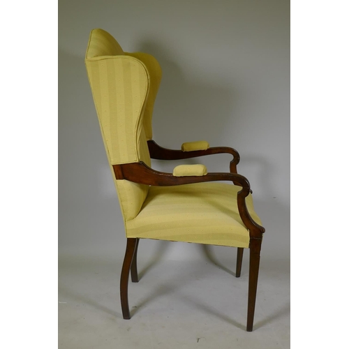 1164 - An Arts & Crafts mahogany wing back armchair with open arms, raised on square tapering supports ... 