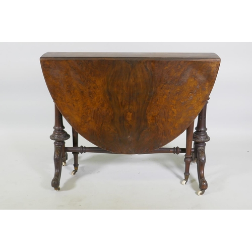 1170 - A Victorian figured walnut Sutherland table, raised on turned and carved end columns with cabriole s... 