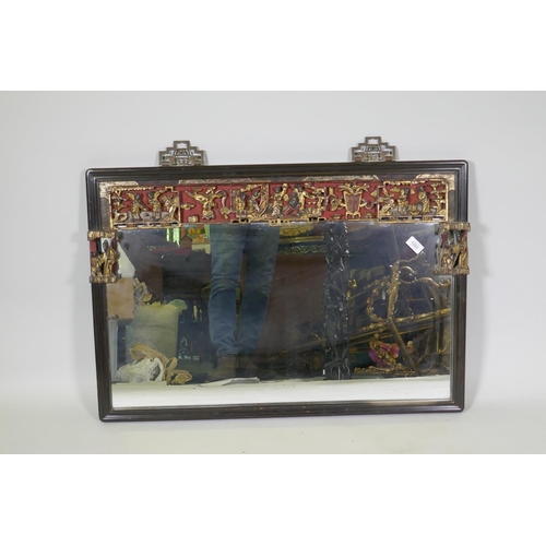 1202 - A Chinese lacquered wall mirror with carved, painted and parcel gilt frieze, early C20th, 90 x 62cm