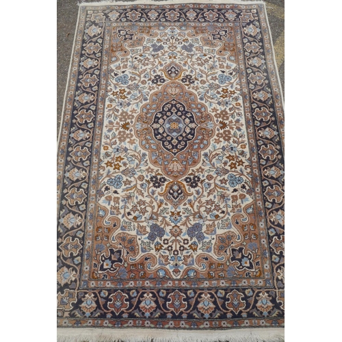 1217 - Oriental wool carpet with medallion design on an ivory field with blue borders, 123 x 195cm