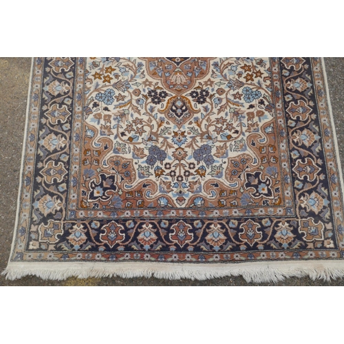 1217 - Oriental wool carpet with medallion design on an ivory field with blue borders, 123 x 195cm