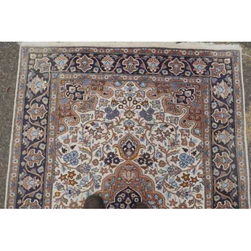 1217 - Oriental wool carpet with medallion design on an ivory field with blue borders, 123 x 195cm